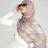 Eine Frau trägt einen Leinen-Baustoff-Hijab-Schal mit Aquarelldruck in beige- und weißlichen Tönen.