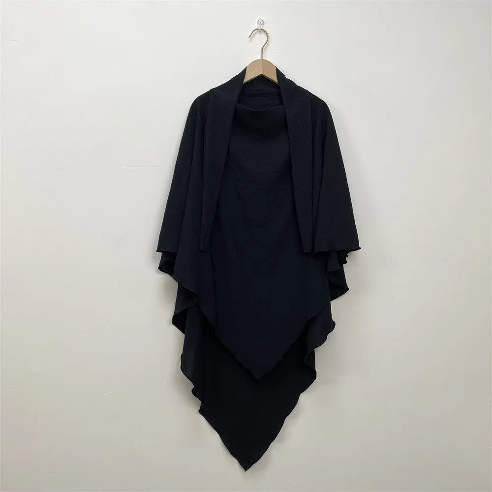 A black two-layer everyday hijab scarf draped on a wooden hanger against a white wall.