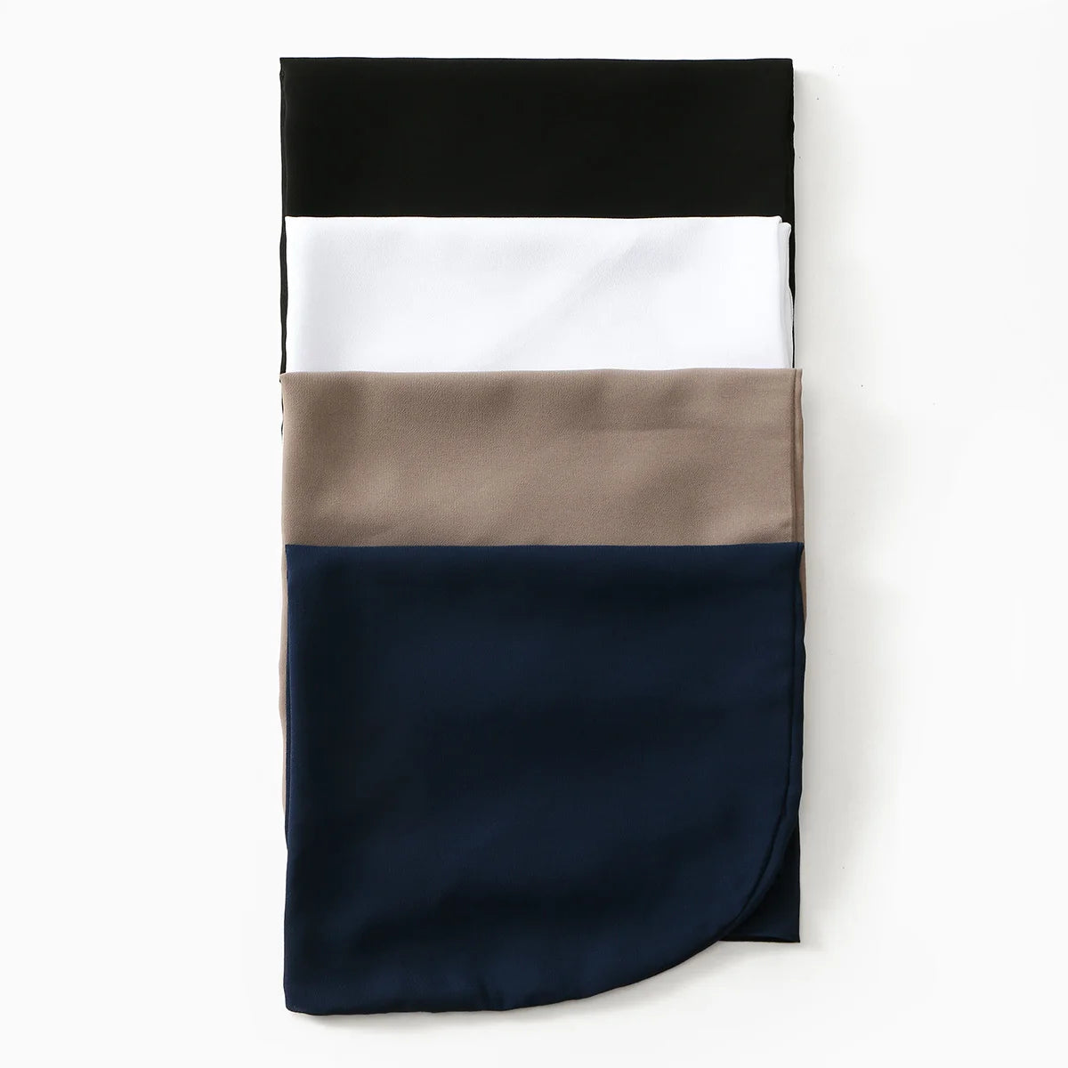 Una pila de cuatro pañuelos de hijab de gasa en negro, blanco, topo y azul marino.