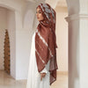 A woman wearing a brown and white watercolor print modal scarf draped over her head in a bright interior.