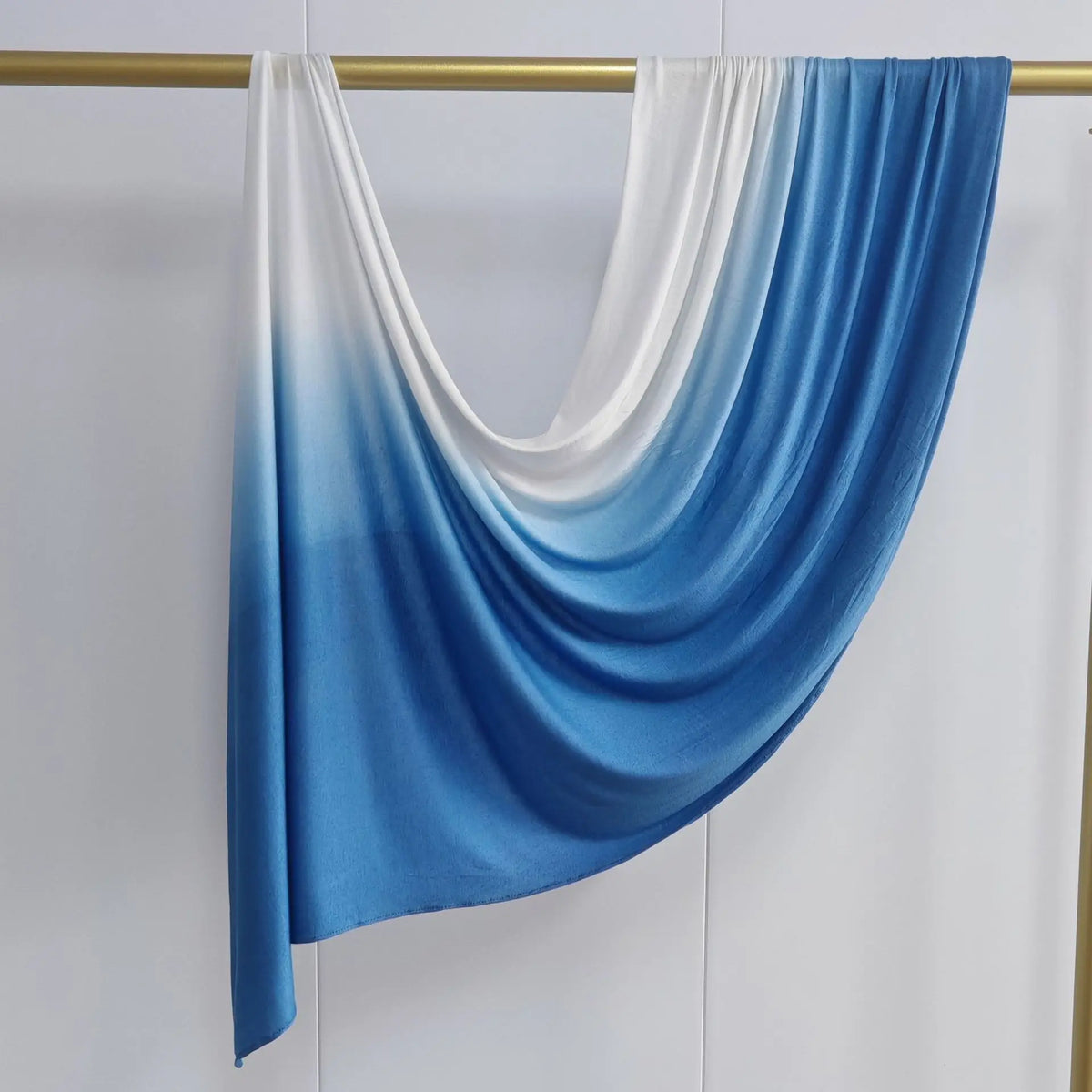 Pañuelo de algodón con degradado azul a blanco, doble cara, colgado en una varilla.