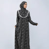 A woman wearing an elegant black and white patterned Muslim hijab dress with lace trim.