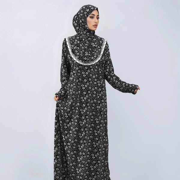 A woman wearing an elegant black and white patterned Muslim hijab dress with lace trim.