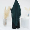 Dunkel-türkises, zweilagiges Chiffon-Niqab-Kopftuch, neben trockenem Ziergräser und einer weißen Box.