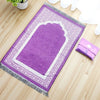 Alfombra de oración musulmana morada con bordado y flecos blancos sobre un suelo de madera.
