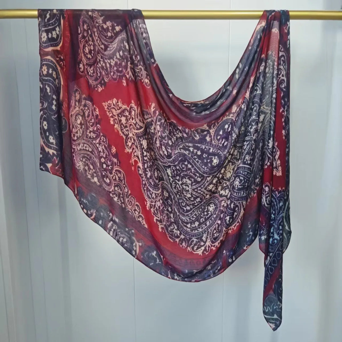 Fließender, mehrfarbiger Hijab-Schal in Rot-, Violett- und Grautönen an einer goldenen Kleiderbügel