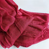 Gros plan d'un foulard hijab en viscose coton rouge profond avec des bords effilés.
