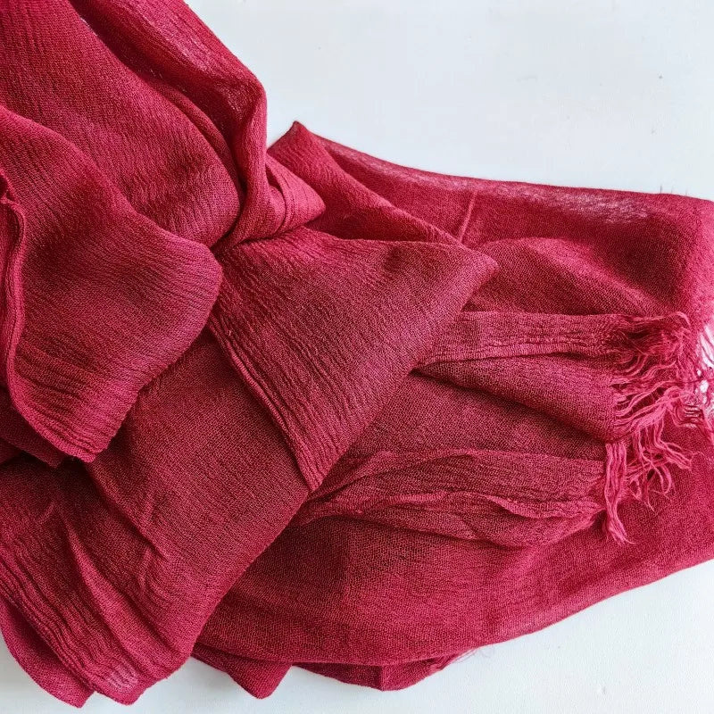 Gros plan d'un foulard hijab en viscose coton rouge profond avec des bords effilés.