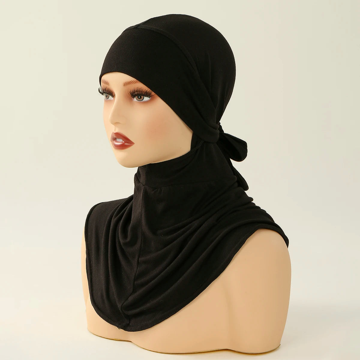 Una mujer modela un elegante hiyab negro de cobertura total con un lazo.