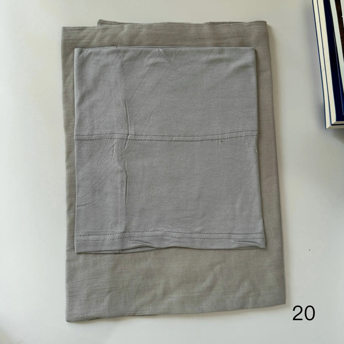 A folded light gray soft modal rayon hijab set for women displayed on a white surface.