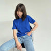 Una mujer vistiendo una camiseta básica de algodón azul real oversize y jeans de lavado claro, sentada en una silla.