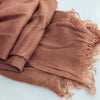 Gros plan sur un foulard hijab en coton viscose brun rouille avec frange et pompon.