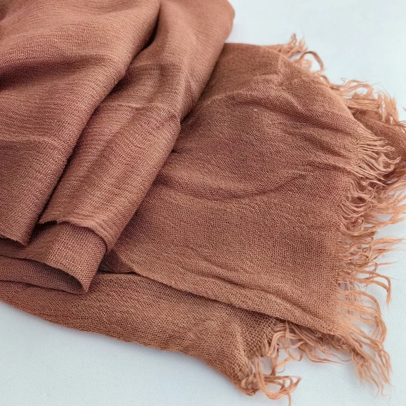 Gros plan sur un foulard hijab en coton viscose brun rouille avec frange et pompon.