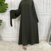 Elegante, dunkelolivgrüne Maxi-Abaya für Damen vor einer weißen Paneelwand.