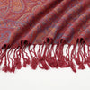 Primer plano de un chal bordado estilo paisley vintage rojo granate con bordes de flecos.