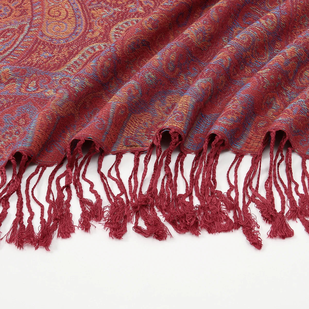 Primer plano de un chal bordado estilo paisley vintage rojo granate con bordes de flecos.