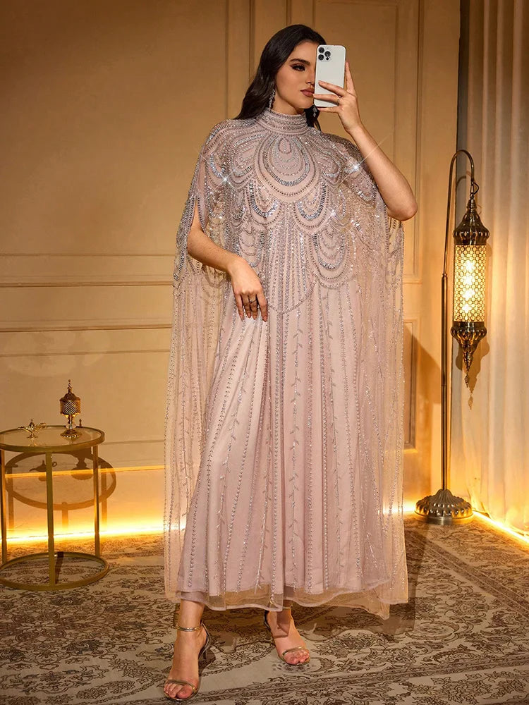 Una mujer modela una elegante bata de ala de murciélago larga en rosa empolvado con delicados bordados.