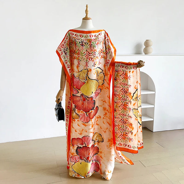 A woman models a loose summer kaftan dress in orange and pink floral print with an accompanying scarf.