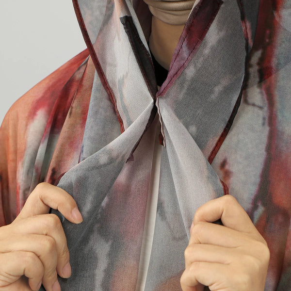 A close-up of a gray and red watercolor chiffon instant hijab draped around the neck.