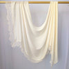 Hijab de gasa color crema drapeado sobre un perchero de madera.