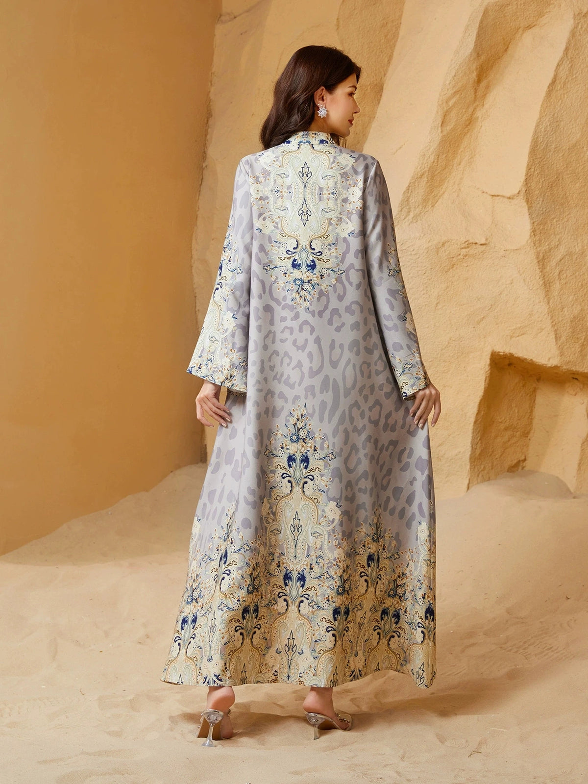 Una mujer vistiendo una abaya larga y fluida de estampado leopardo en marfil y azul con adornos de diamantes