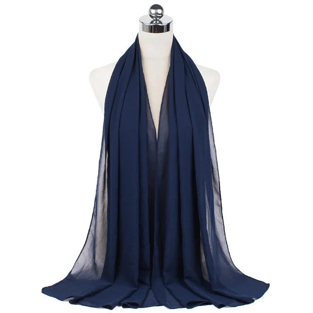 A dark navy blue chiffon hijab scarf draped around a mannequin's neck.