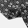 Black fabric with white floral and polka dot pattern, showing a folded section of an elegant Muslim hijab dress.