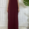 Langes, maroones ärmelloses Kaftan-Kleid auf einem Mannequin vor einer weißen Wand mit Paneelen.