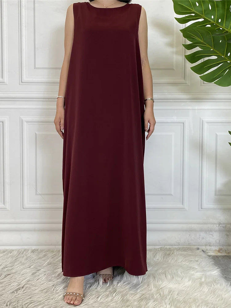 Langes, maroones ärmelloses Kaftan-Kleid auf einem Mannequin vor einer weißen Wand mit Paneelen.