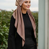 Una mujer vistiendo hijab beige y ropa negra con una diadema de diamantes.