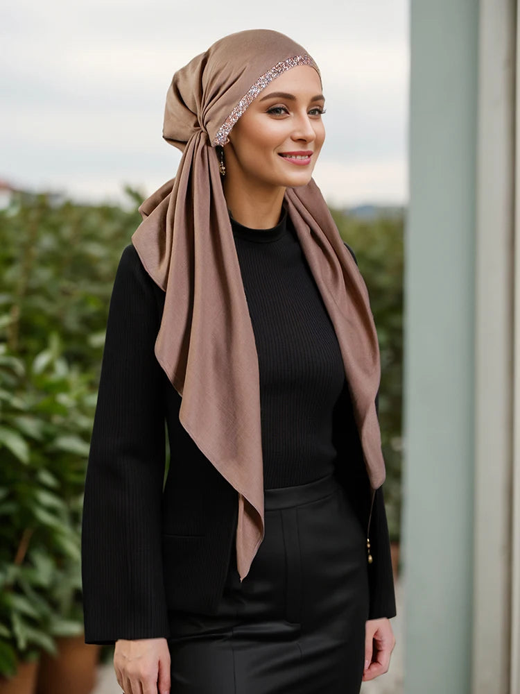 Una mujer vistiendo hijab beige y ropa negra con una diadema de diamantes.