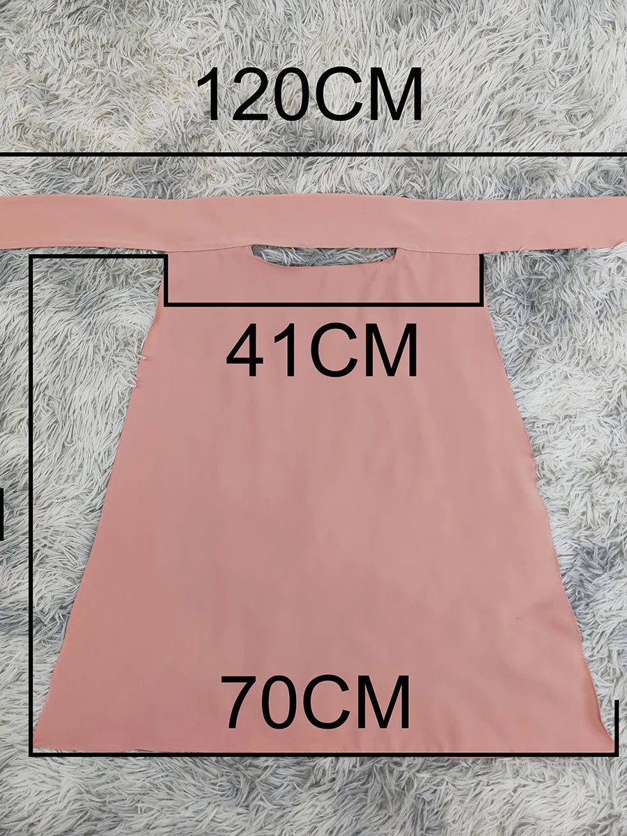 Elegane rosa Maxi-Abaya für Damen vor grauem, strukturiertem Hintergrund.