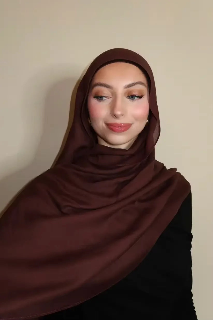 Eine Frau trägt einen einfarbigen braunen Gradient-Rayon-Modalfoulard und schwarze Kleidung.