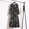 Schwarzes Maxi-Kleid mit bohemienartigem Blumenmuster an einem Holzbügel.
