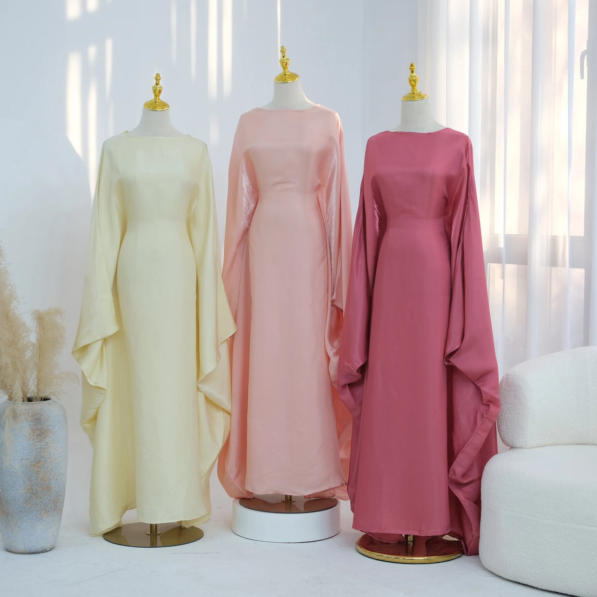 Langes pinkes Kaftankleid mit Schmetterlingsärmeln auf einem Mannequin.