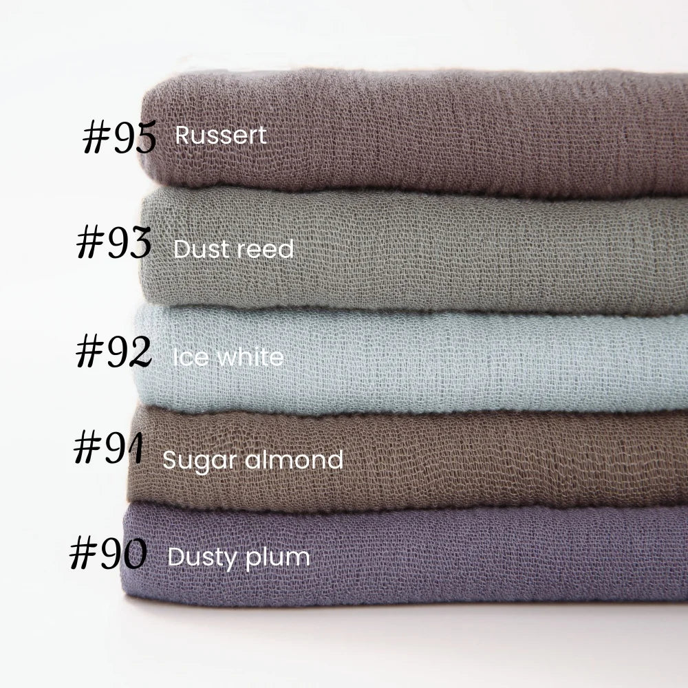 Pile de neuf foulards de hijab en coton viscose doux dans diverses nuances sourdes, dont roux, rose pâle, blanc glacé et aman