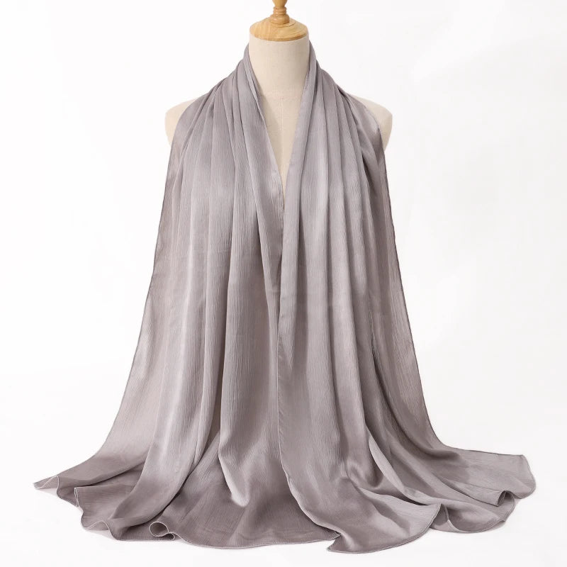 Ein drapierter, fließender grauer Satin-Crinkle-Hijab-Schal auf einem Mannequin.