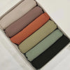 Ein Set von sechs Chiffon-Hijabs in Pastelltönen, beige, pink, orange und grün, in einer Box angeordnet.