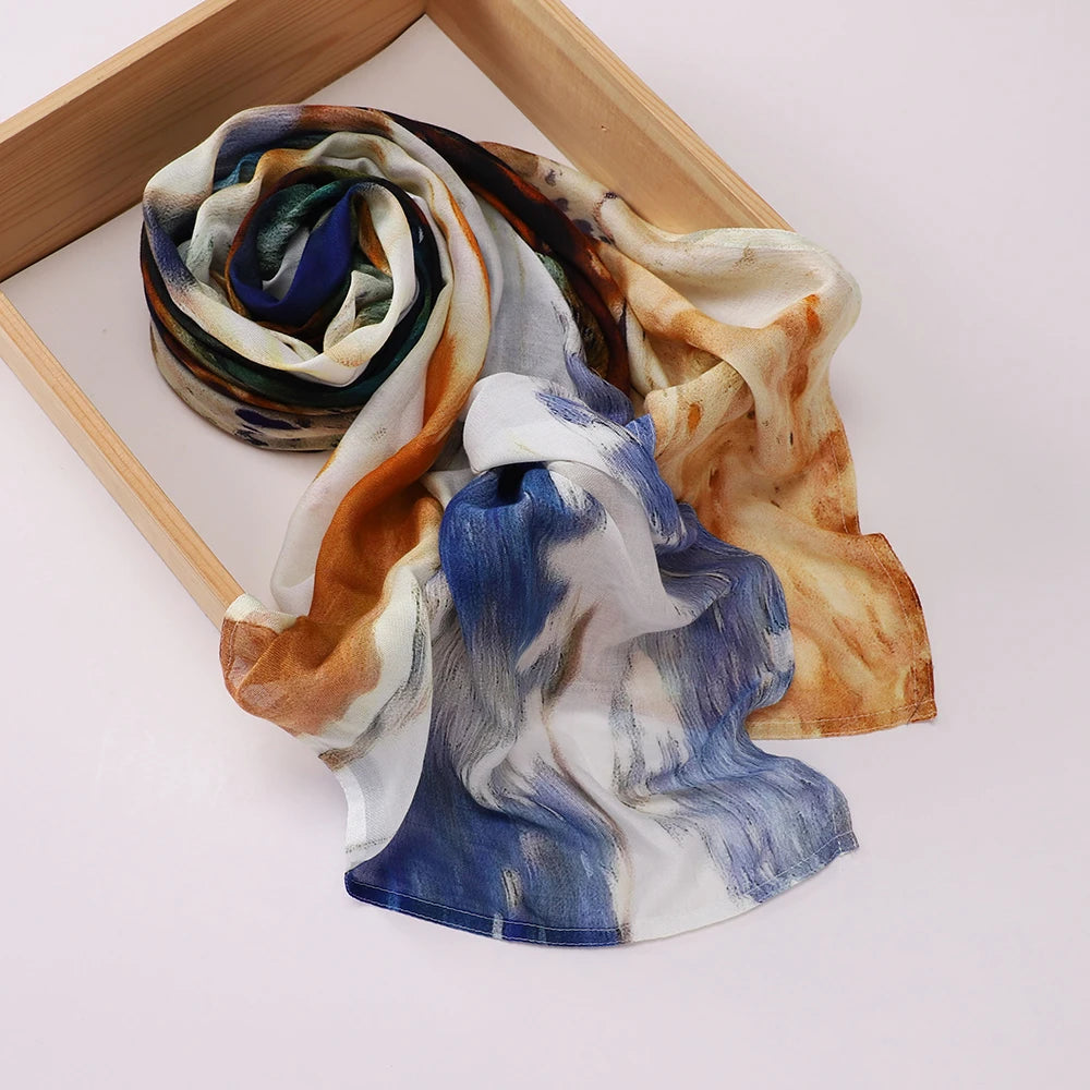 Voile hijab imprimé élégant drapé, aux tons de bleu, blanc et orange brûlé, exposé dans un cadre en bois.