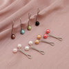 Collection de foulards hijab multicolores avec boucles métalliques décoratives et perles sur fond rose.