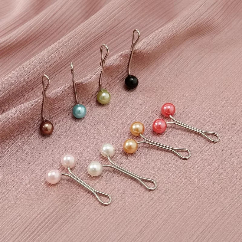 Collection de foulards hijab multicolores avec boucles métalliques décoratives et perles sur fond rose.