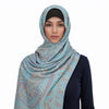 Una mujer vistiendo un pañuelo pashmina de lujo con estampado azul claro y verde azulado