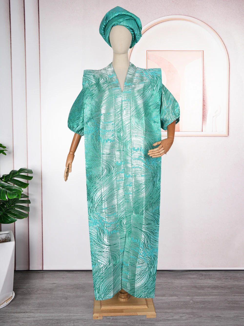 A woman wearing a teal satin kaftan abaya with a matching headscarf displayed on a mannequin.