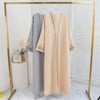 Beige, offene Maxi-Abaya mit Blumenstickerei auf einem Bügel.