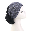 Turban elegante de flores y perlas con encaje negro, exhibido en maniquí.