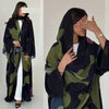 Modelo vistiendo un conjunto de abaya de gasa estampada en negro y verde oliva con hijab negro.