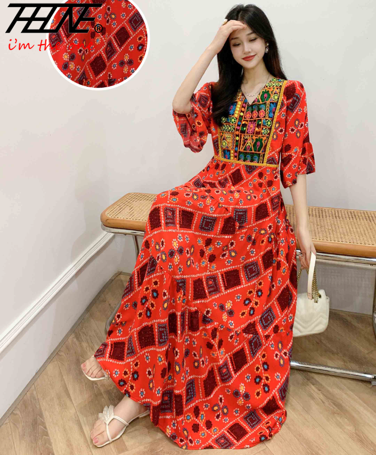 Eine Frau modelliert ein leuchtend rotes, bohemiss-besticktes Maxi-Kleid mit farbenfrohen Mustern und Ärmeln.