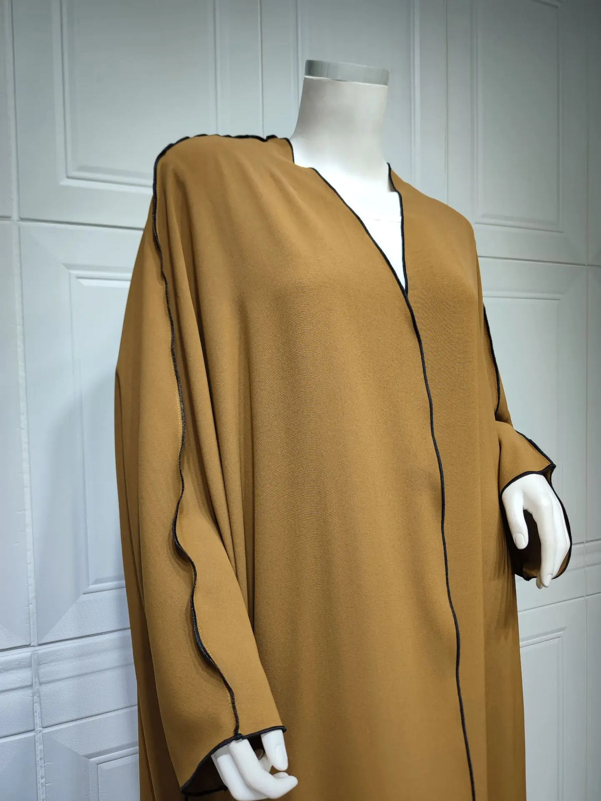 Vestido abaya color camello de largo completo y grande, exhibido en maniquí contra fondo blanco acristalado.