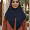 Une femme portant un foulard instant bleu marine et un haut orange, dans un cadre ensoleillé extérieur.