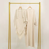 A beige elegant two-piece abaya and khimar set displayed on a gold hanger against a white background.